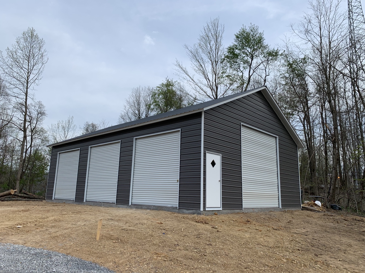 Charcoal metal garage with multiple white roll-up doors